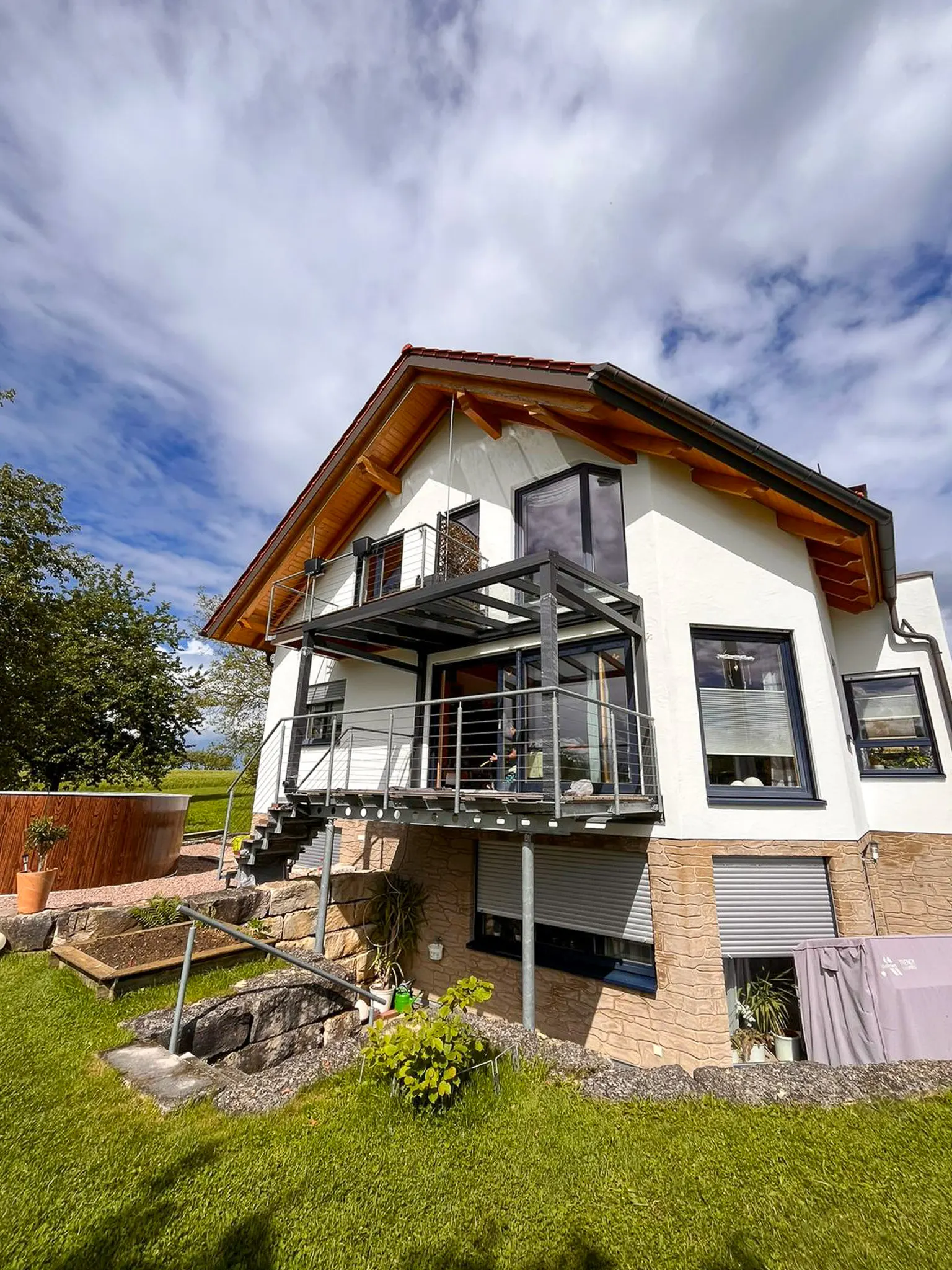 Terrassenüberdachung mit Treppen­aufgang an zweistöckigem Haus