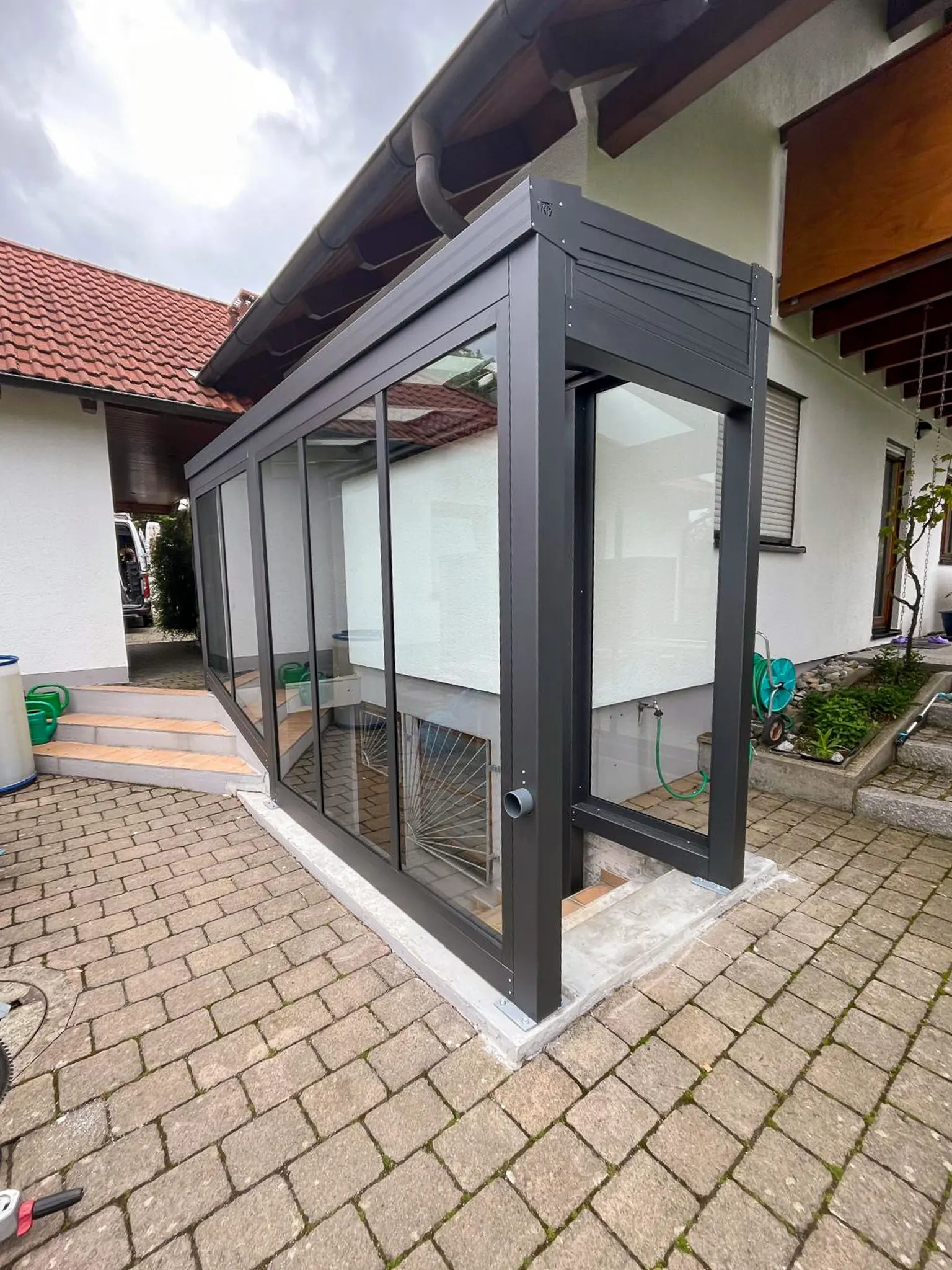 Kompakter Wintergarten aus Aluminium und Glas an Hauseingang