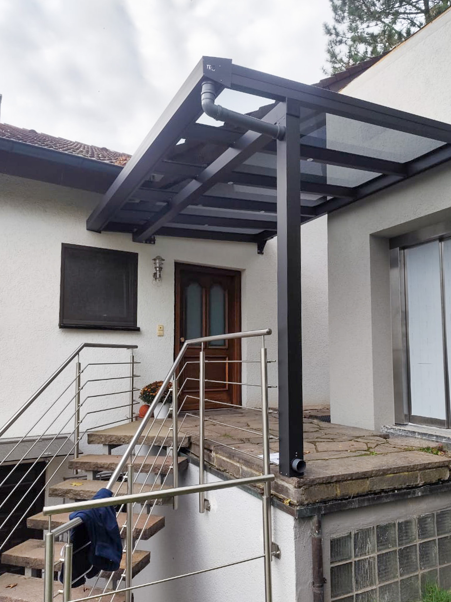 Eingangsüberdachung KD Sky aus Aluminium und Glas an Einfamilienhaus mit Treppen­aufgang